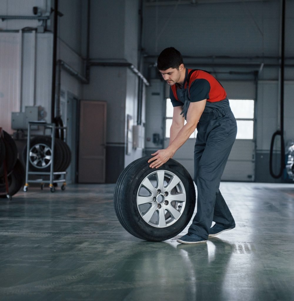 one-last-wheel-mechanic-holding-a-tire-at-the-repair-garage-replacement-of-winter-and-summer-tires.jpg